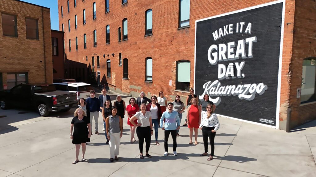 The LKF team poses next to the Make it a great day, Kalamazoo mural in Haymarket Plaza.