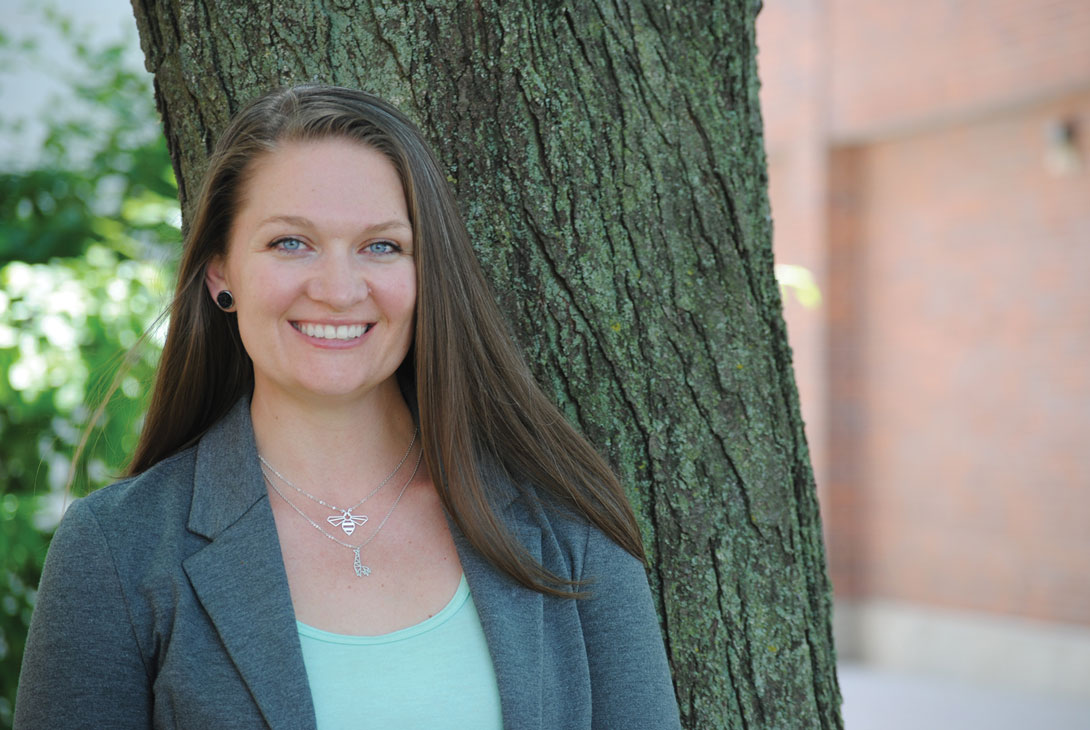 Lisa Moore stands next to a tree smiling.